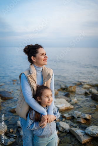 family weekend by the sea. happy mother and daughter have fun on a walk. sunset on the sea