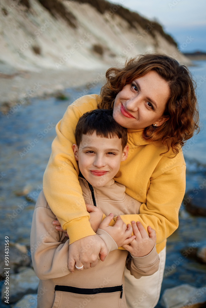 family walk on the seashore in the cold season. happy mother and son hugging each other family walk on the seashore in the cold season. happy mother and son hugging each other