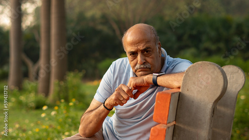 Senior citizen man sitting on bench in park
