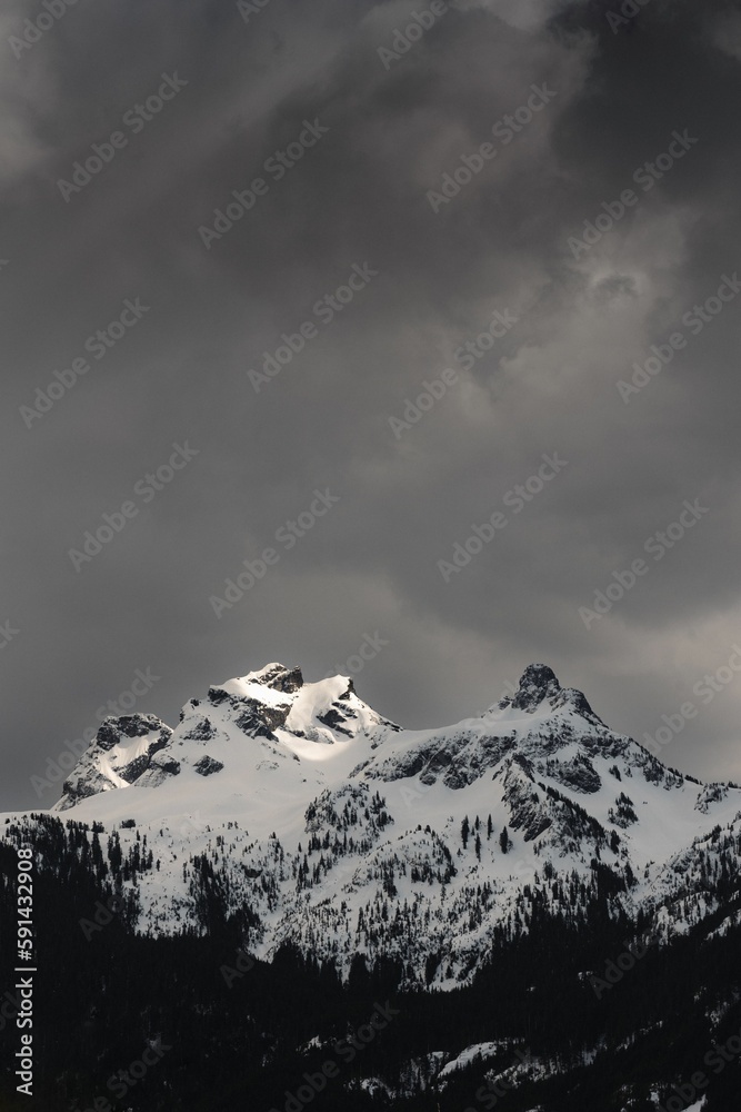 Vertical aerial view of snowcap rocky mountains against dark gray cloudy sky Vertical aerial view of snowcap rocky mountains against dark gray cloudy sky