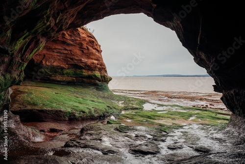 Natural arch and cliffs before a sea in Nova Scotia, Canada on a clouded day