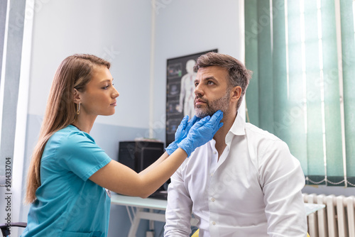Endocrinologist examining throat of man in clinic. Men with thyroid gland test . Endocrinology, hormones and treatment. Inflammation of the sore throat photo