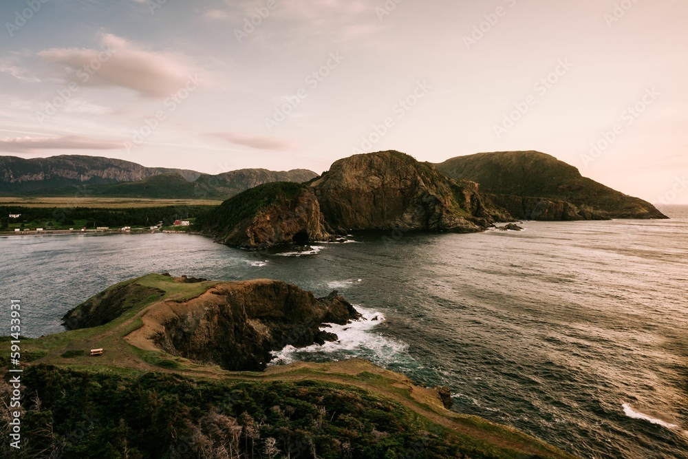 High-angle shot of the mountains and the sea under the sunset at the cloudy sky.