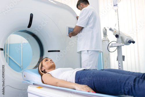 The patient lies on CT or MRI  the bed is moved inside the machine  scanning her body and brain under the supervision of a doctor  radiologist. In a medical laboratory with high-tech equipment.