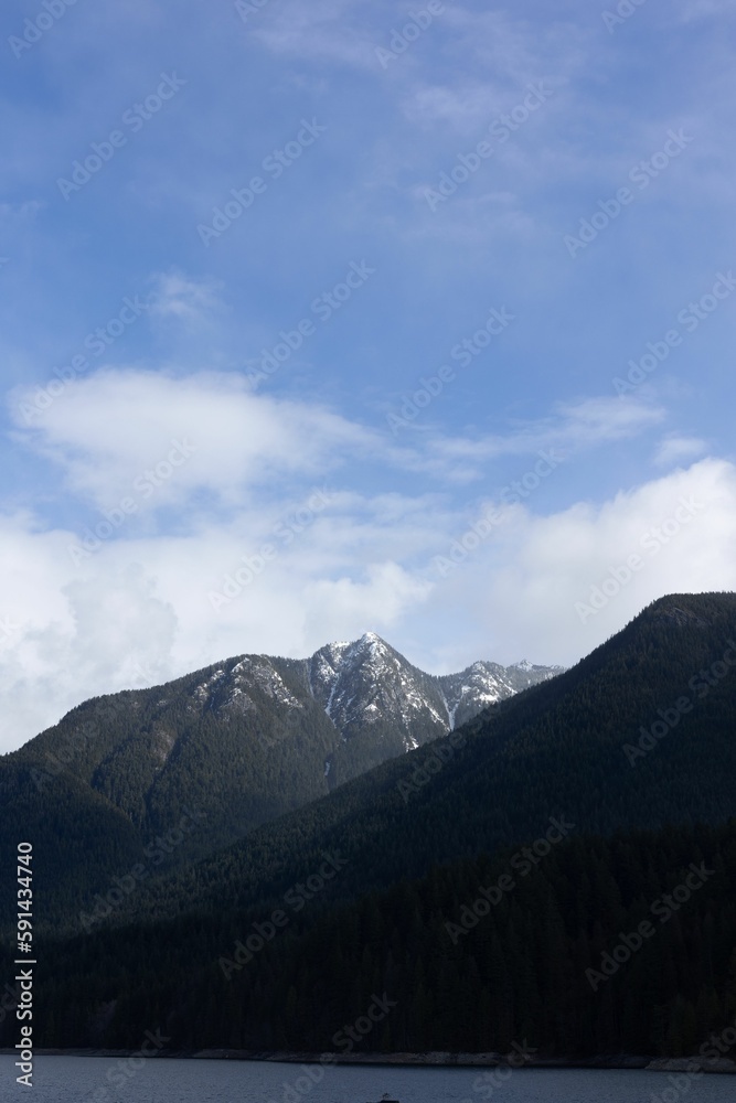 Fototapeta premium a boat floating near the shore of a lake with mountains in the background