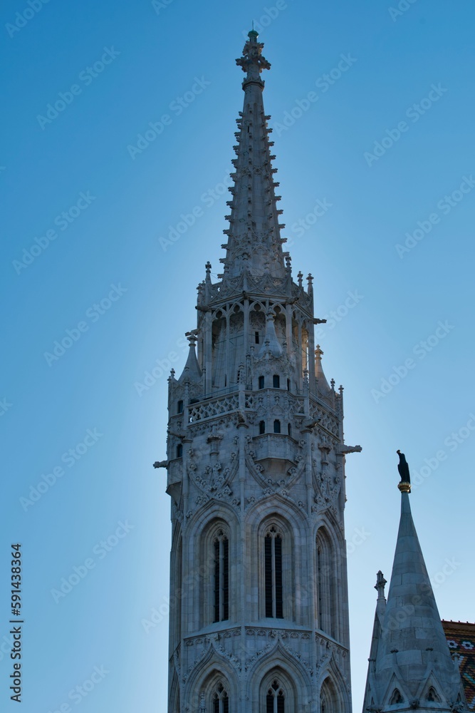 Vertical shot of the Matthias Church tower against a blue sky in Budapest, Hungary