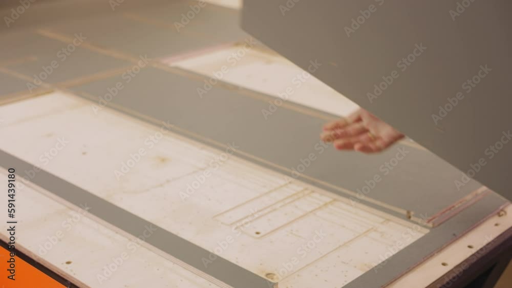 Worker takes rectangle plywood detail cut by lathe machine in woodwork shop closeup. Carpenter checkups part of furniture and home decor in studio Worker takes rectangle plywood detail cut by lathe machine in woodwork shop closeup. Carpenter checkups part of furniture and home decor in studio