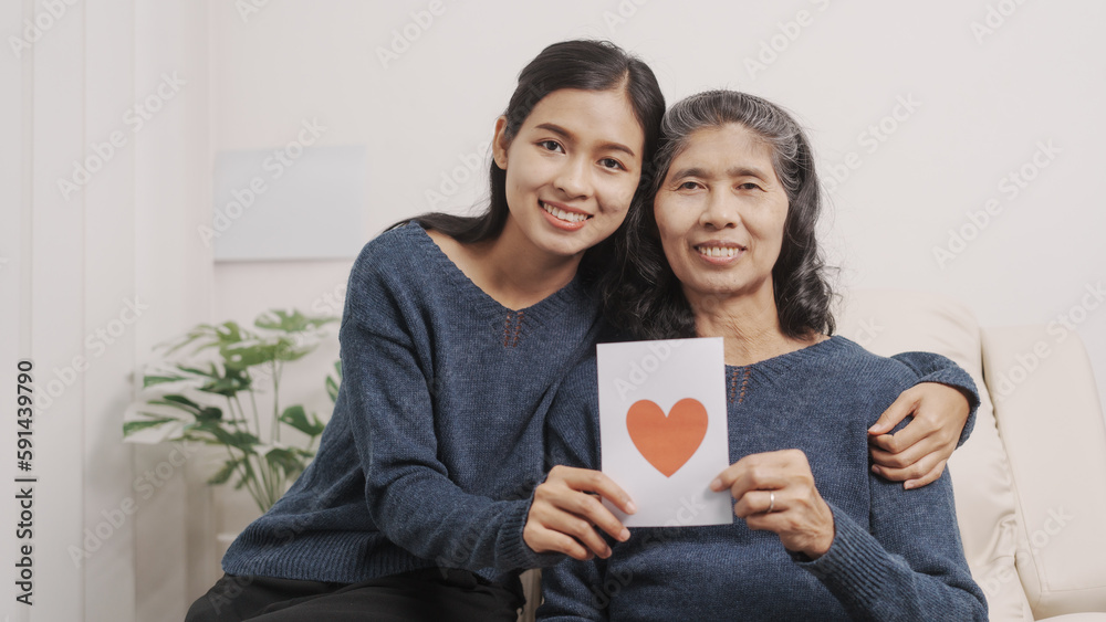 Greeting card, Mother's day concept, young adult female daughter congratulate excited asian elderly mother at sofa with birthday anniversary, two generations family photo, real people. Greeting card, Mother's day concept, young adult female daughter congratulate excited asian elderly mother at sofa with birthday anniversary, two generations family photo, real people.