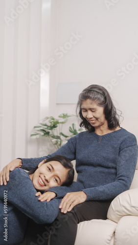 Mother's day concept, young adult female daughter congratulate excited asian elderly mother at sofa with birthday anniversary, two generations family photo, real people.