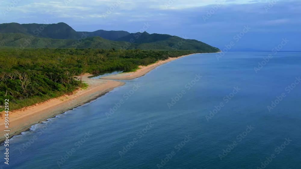 Drone shot over Wangetti beach with forest and green mountains around, cloudy sky background Drone shot over Wangetti beach with forest and green mountains around, cloudy sky background