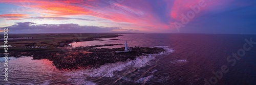 Drone shot of the St Mary's Lighthouse on the rocky coast in UK at sunset