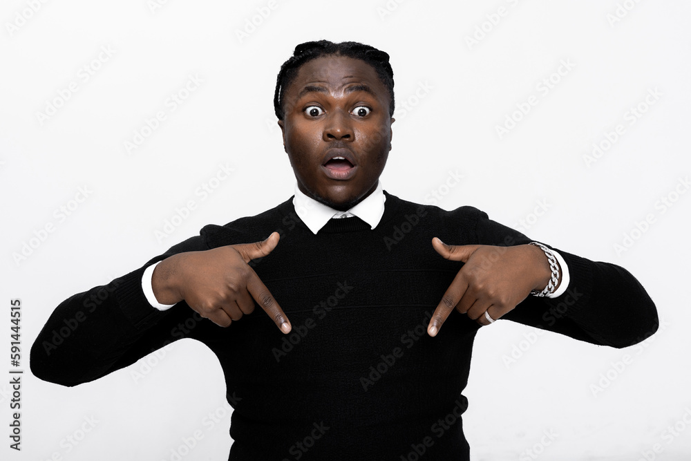 Surprised excited american man in casual black sweater hoodie pointing down with opened mouth amazed and cheerful emotions standing over white background in studio isolated. Surprised excited american man in casual black sweater hoodie pointing down with opened mouth amazed and cheerful emotions standing over white background in studio isolated.