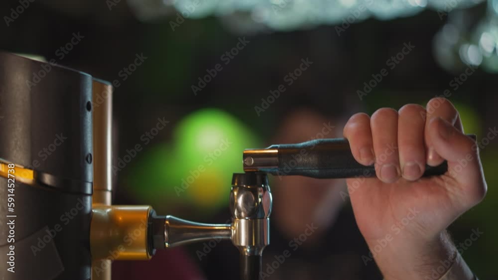 Barman turns beer pump lever to pour drink at counter in pub closeup. Bartender uses beverage dispenser working in brewery. Restaurant employee