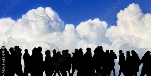 black silhouettes of people walking against the background of a cloud and blue sky