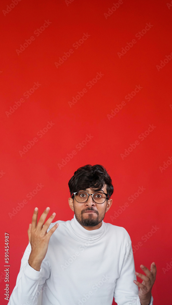 Annoyed face. Angry shrug. Stress frustration. Portrait of mad displeased man in glasses outraging on red color empty space background. Annoyed face. Angry shrug. Stress frustration. Portrait of mad displeased man in glasses outraging on red color empty space background.