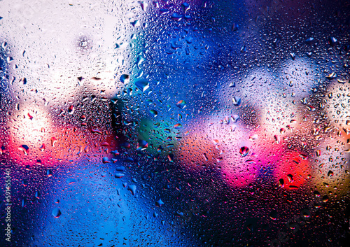 City view through a window on a rainy night,Rain drops on window with road light bokeh, City life in night in rainy season abstract background. Focus on drops on glass 
