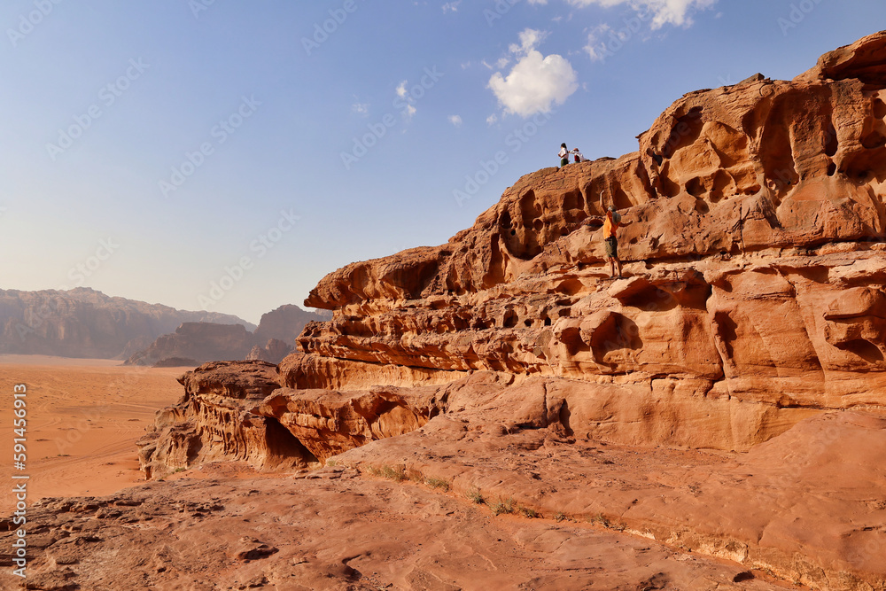 touists on rock formations visiting wadi rum desert