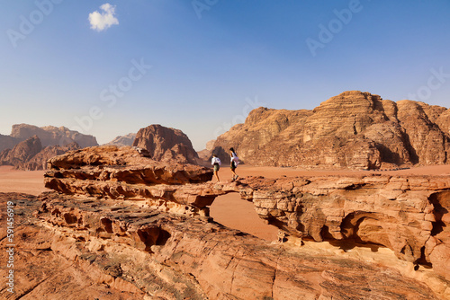 two tourists walking on small stone bridge in wadi rum desert