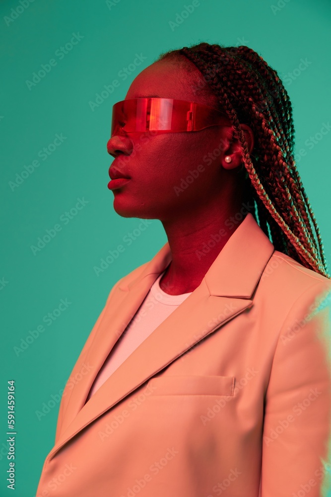 Fototapeta premium African american woman smile and fashion wearing glasses green background in neon light color mixed light, bright color dancing, futuristic party. Beauty African American woman with pigtails emotions.