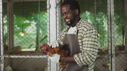 A male African farmer gently holds and talks to a chicken
