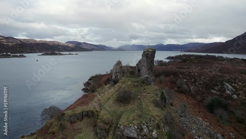 Revealing orbit drone shot of the Caisteal Maol ruins on a hill overlooking Kyleakin harbour and the loch and mountains of Isle of Skye, Scotland. photo