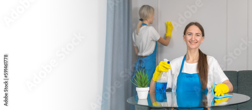 Staff of the cleaning service with professional equipment is engaged in cleaning the house, hygiene. Young woman in uniform wipes the table with a cleaning agent, microfiber cloths. Banner