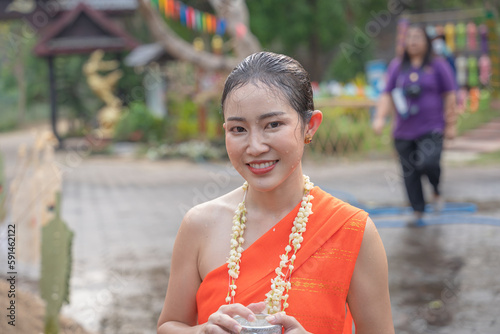 Tourist Asian people wearing traditional Thai dresses are happy to play splashing water during Songkran festival for travel a funny happy holiday in popular culture Thailand.