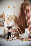 children's room in scandinavian style. canopy in the interior, storage of toys, a little girl plays