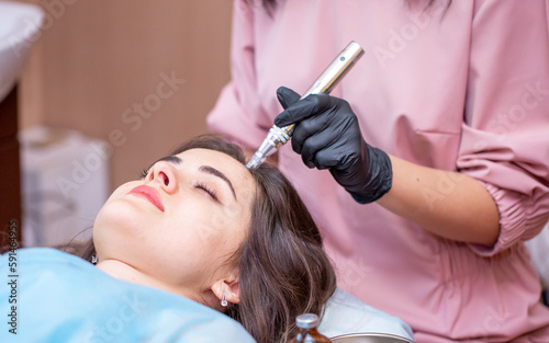 Treatment of the scalp for hair loss, alopecia. A trichologist doctor makes a dermapen procedure on the patient's head. Vitamin injections to improve hair growth. photo
