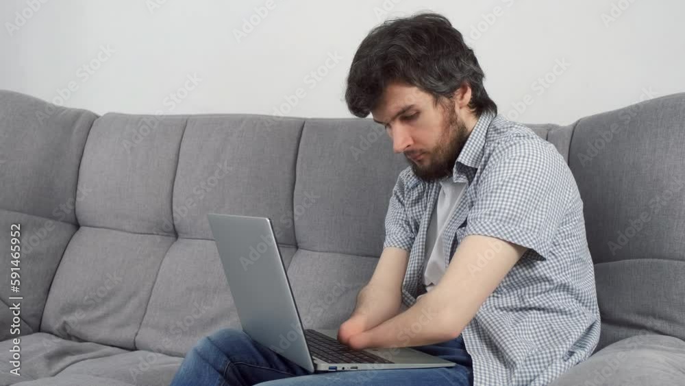 Handicapped Disabled man with amputated two stump hands working typing on laptop at home office sitting on sofa. Problem adaptation to life people with disabilities. Independent Invalid person. Handicapped Disabled man with amputated two stump hands working typing on laptop at home office sitting on sofa. Problem adaptation to life people with disabilities. Independent Invalid person.