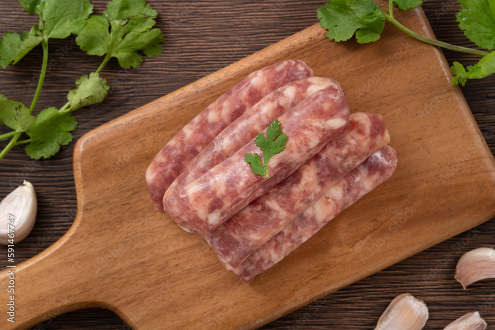 Raw Taiwanese sausage in garlic flavor in a plate on wooden table background. Raw Taiwanese sausage in garlic flavor in a plate on wooden table background.