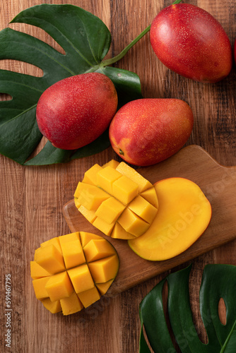 Fresh mango fruit with leaves over dark wooden table background.