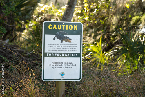 Alligators warning sign in Florida state park about caution and safety during trail walk