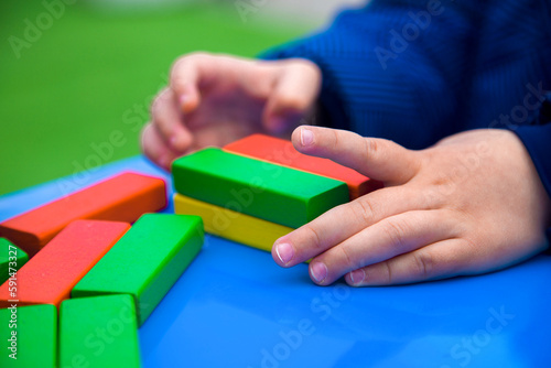 close-up of children's hands building a tower of multi-colored bars 