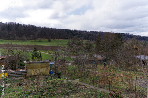 Scenic view over rural landscape and agriculture fields with garden plot in the foreground on a cloudy winter day. Photo taken February 26th, 2023, Zurich, Switzerland.