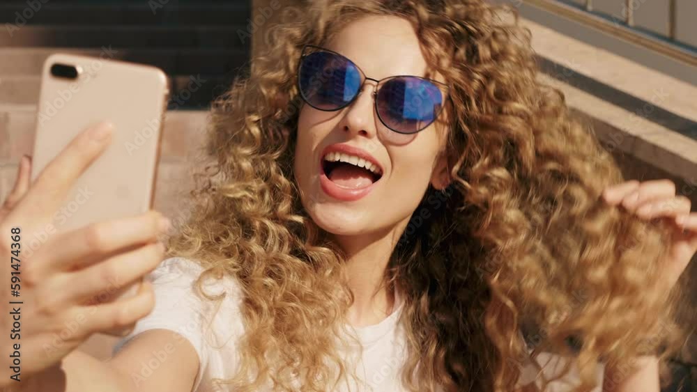 Portrait of beautiful smiling model with afro curls hairstyle dressed in summer hipster clothes. Sexy carefree girl in the street background. Trendy funny and positive woman having fun. Taking selfie Portrait of beautiful smiling model with afro curls hairstyle dressed in summer hipster clothes. Sexy carefree girl in the street background. Trendy funny and positive woman having fun. Taking selfie