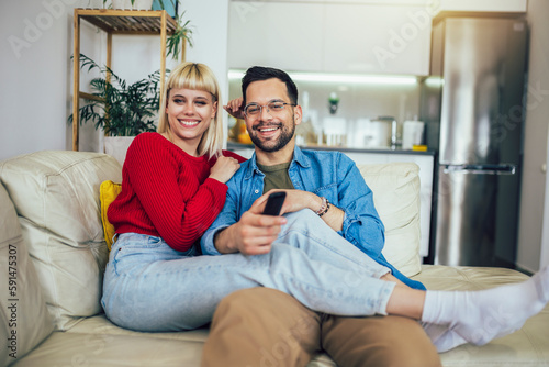 Beautiful couple hugging relaxing on sofa and watching tv. Love,happiness,people and fun concept.