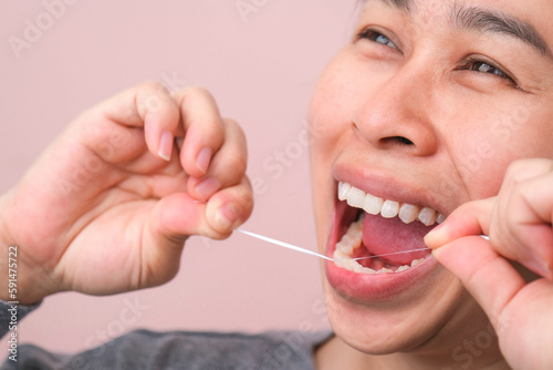 Close-up of smiling asian woman and cleaning for perfect smile. Healthy white teeth by flossing  oral health and dental care.