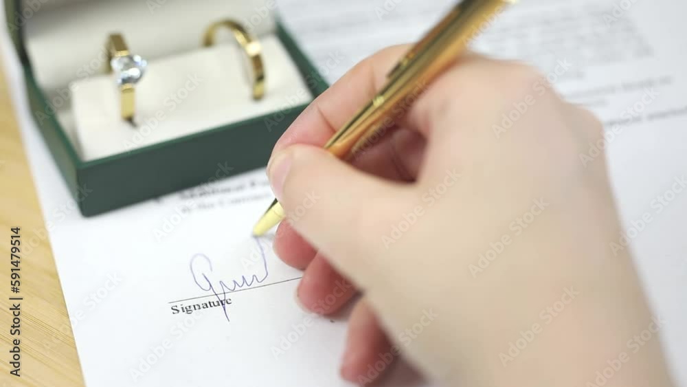 Hand Signing Marriage Contract Golden Wedding Rings With Gold Pen On Hand Signing Marriage Contract Golden Wedding Rings With Gold Pen On