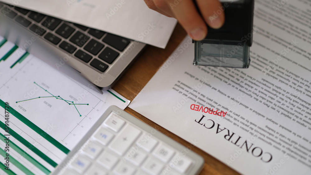 Manager hand putting stamp approved on contract document form in office closeup. Employment and profitable deals concept Manager hand putting stamp approved on contract document form in office closeup. Employment and profitable deals concept