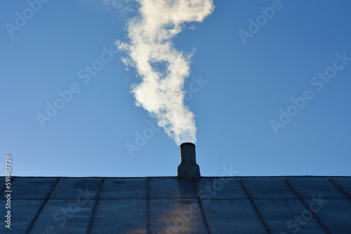 white smoke from burning wood comes out of the chimney of a village house