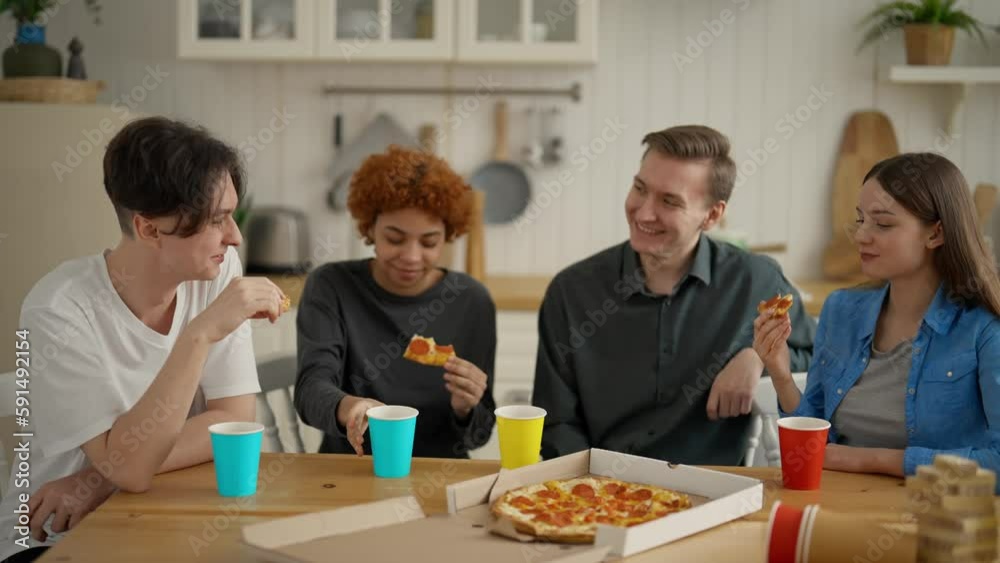 Young happy multi ethnic friends group talking sharing pizza discussing interesting funny news. Students at home together eating, having fun, conversation, laughing and drink beer. Meeting at weekend.