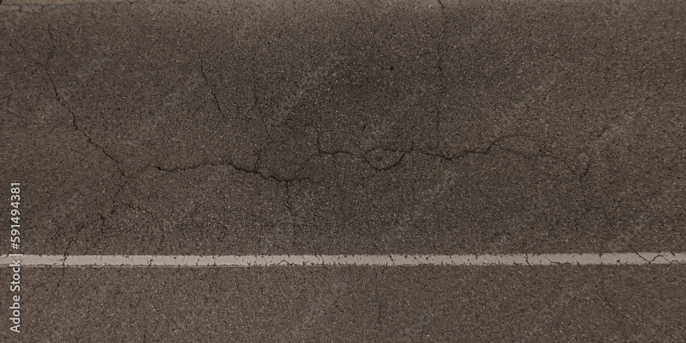 Fototapeta premium top view of surface of asphalt road made of small stones and sand with cracks