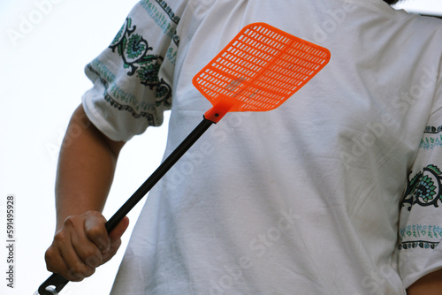 A person holds a fly swatter to smite the annoying flies.