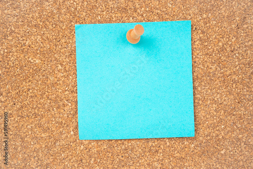 The Blank blue sticky note paper and wooden thumbtack on wooden background.