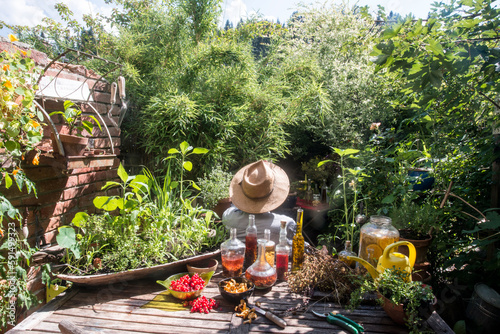 Man wearing hat sitting with fresh oil and homemade vinegar in garden photo
