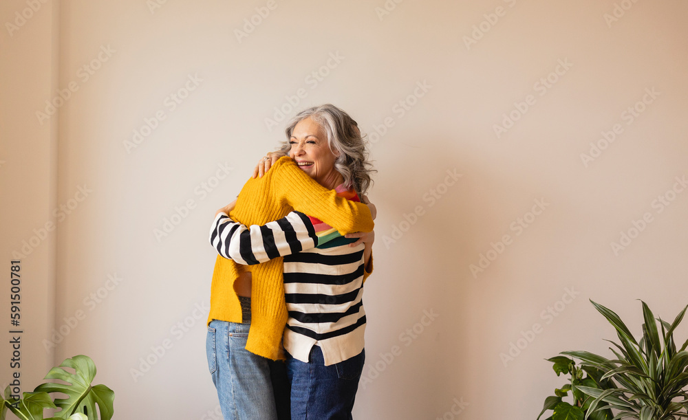 Happy mother hugging daughter in front of wall at home Happy mother hugging daughter in front of wall at home