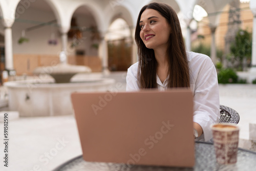 Edit Young charming business woman in white works on the laptop
