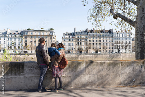 Photography Couple and their little daughter looking at beautiful buildings around Seine riverbank