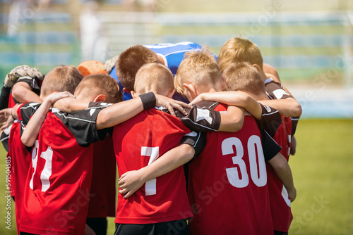 Soccer kids with the coach. Portrait of a friendly football team gathered together with the coach. Boys motivating each other in sports team before the football tournament match